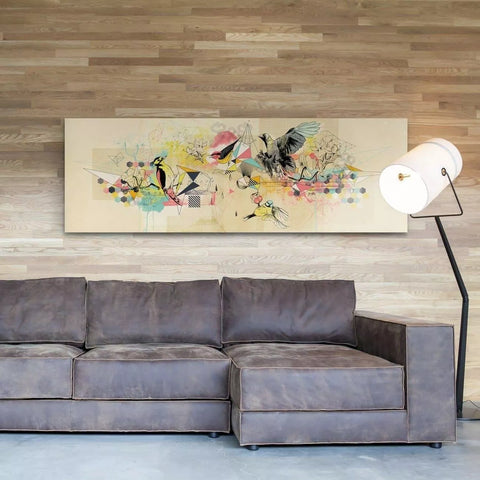Abstract colorful artwork featuring birds and floral elements mounted above a gray sectional sofa.