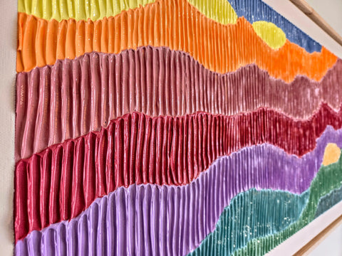 Colorful textile art piece with wavy, pleated fabric strips in various hues arranged horizontally.