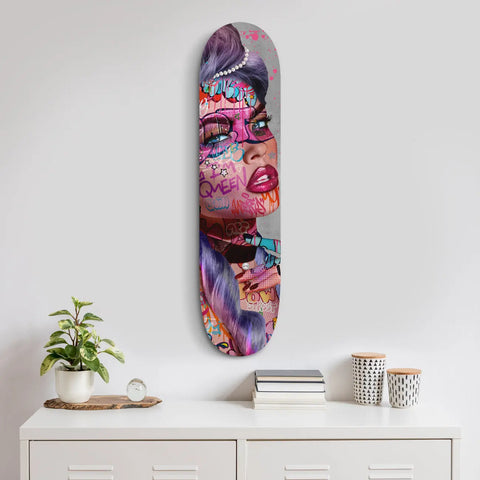 Skateboard deck featuring vibrant pop art-style artwork in pink, purple and blue tones.