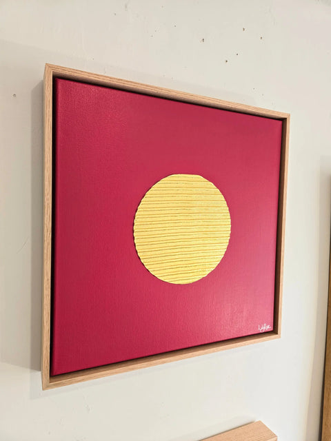 Framed artwork featuring a yellow circle on a red background.