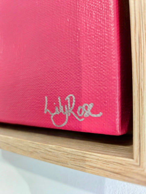 Pink canvas or painting with a silver signature in the corner.