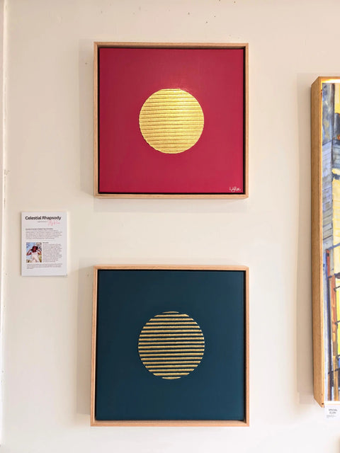 Two framed abstract artworks featuring golden circular shapes on red and blue backgrounds.