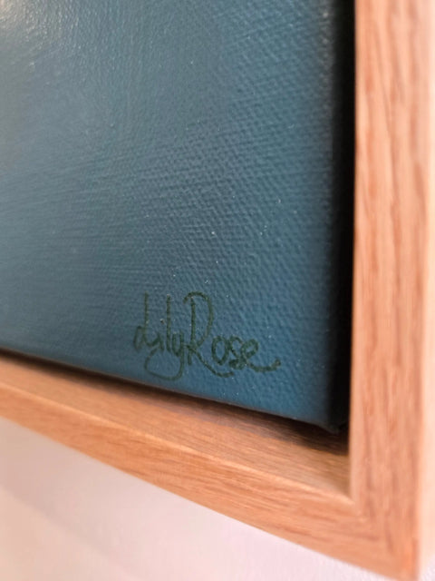 Signature or autograph on a dark blue surface, likely a painting or artwork.
