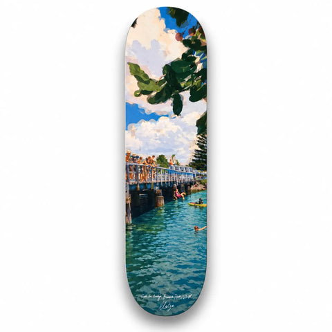A skateboard deck featuring a vibrant beach scene with turquoise water and green foliage from brunswick heads australia keepsake fakeboard