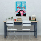 Simple desk setup with two white folding chairs and a colorful pop art poster above.