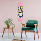Colorful lion face painted on a pink skateboard deck mounted on a wall.