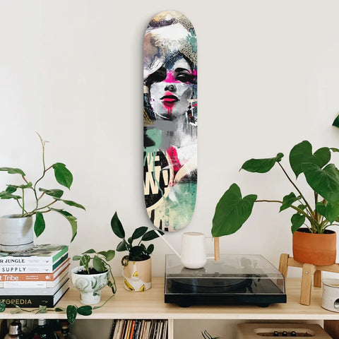 Artistic skateboard deck featuring a stylized portrait in black, white, and pink tones with mint green accents.