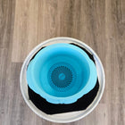 Circular blue pet water bowl with a spiral pattern at the bottom, sitting inside a white container with a black mat.