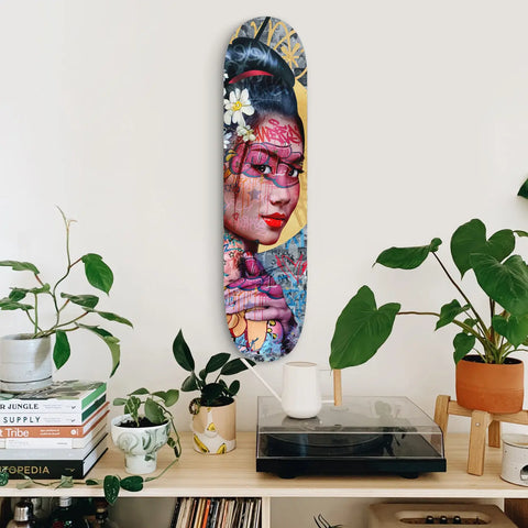 Colorful artistic skateboard deck featuring a portrait painted in vibrant pinks and blues with floral elements.