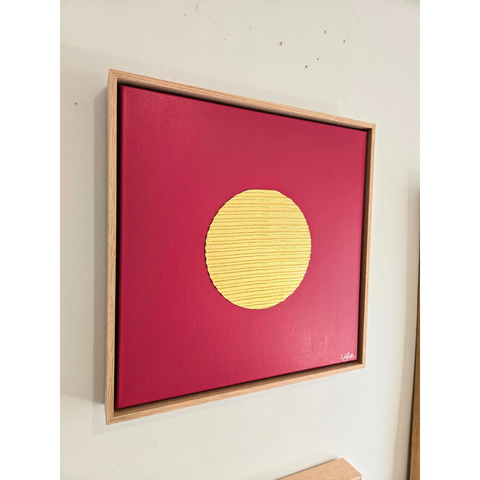 Framed artwork featuring a yellow circle on a red background.