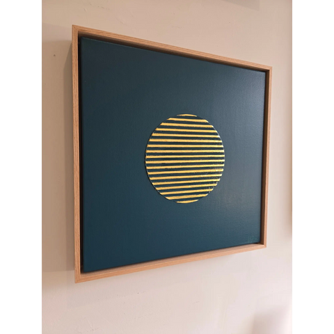 Framed artwork featuring a yellow striped circle on a dark blue background.