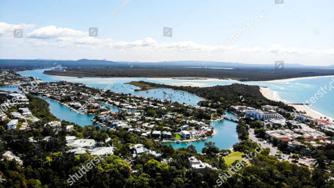 Coastal town with waterways and residential areas nestled between ocean and forest.