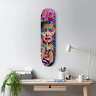 Colorful skateboard deck featuring vibrant pop art-style portrait artwork mounted on a wall.